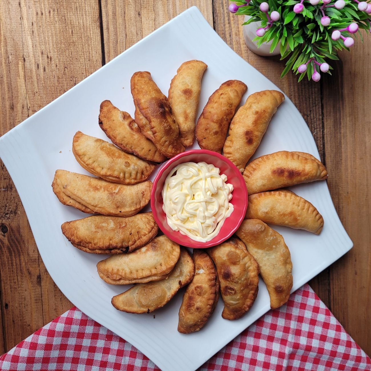 Golden fried dumplings arranged on a plate with a creamy dipping sauce