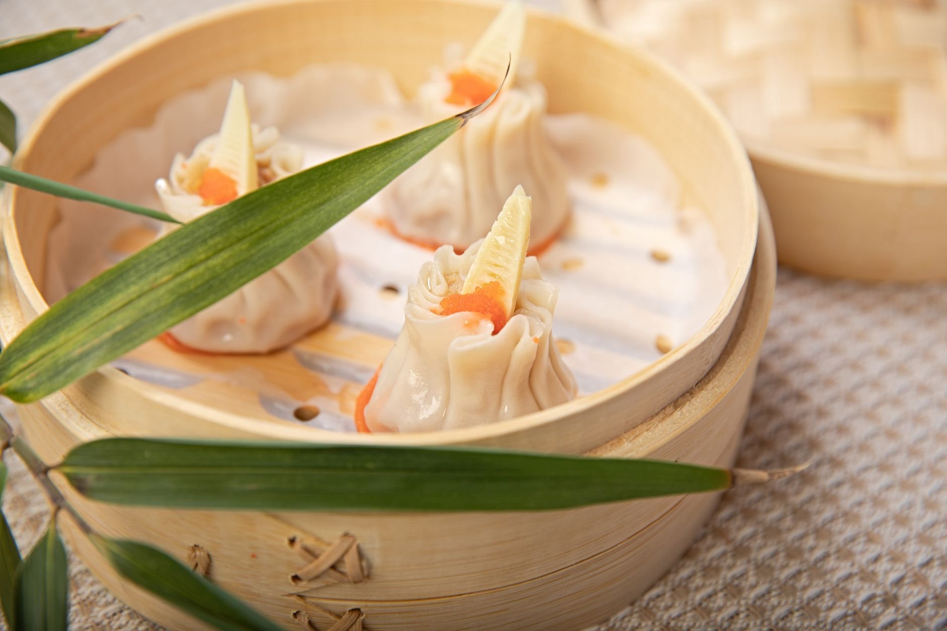 Close-up of freshly steamed dumplings rising with steam from a bamboo basket